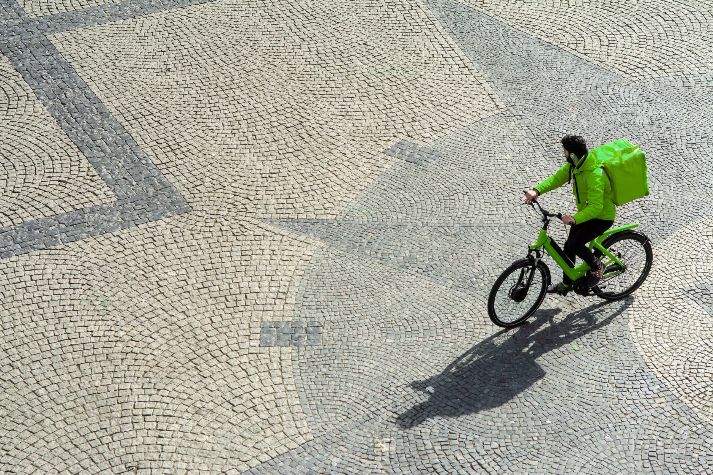 Entregador pedalando uma bike elétrica pela cidade